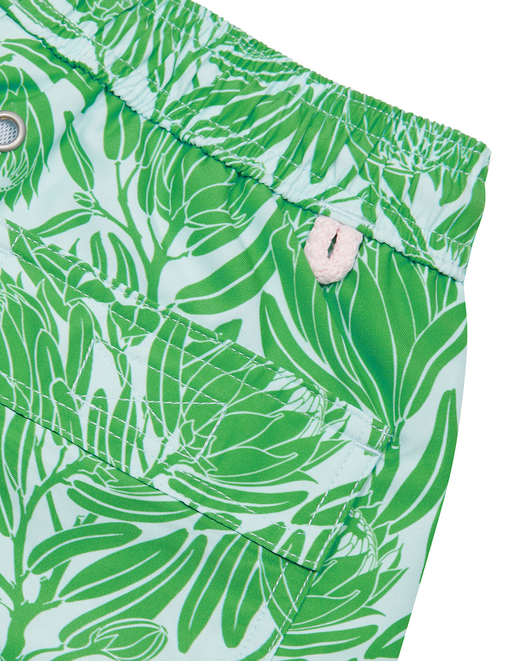 Back pocket detail of kids recycled swim trunks in green Protea print