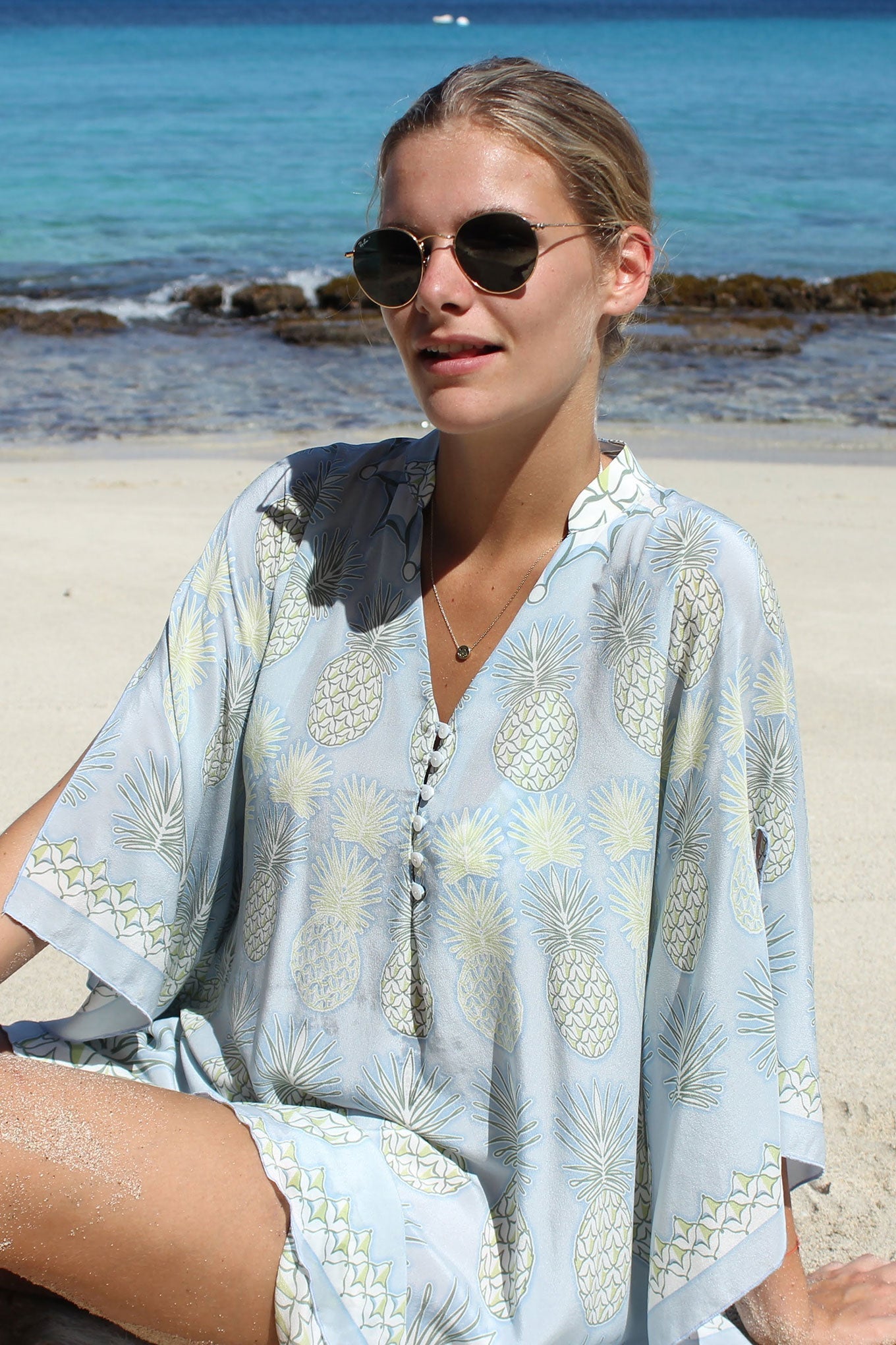 Lotty B Short Kaftan in Silk Crepe-de-Chine: PINEAPPLE - OLIVE sitting on the beach Mustique