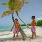 Kids swim shorts in Guava red print by designer Lotty B Mustique holiday style