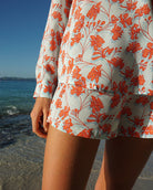 Tropical island style pure silk Kim blouse in floral Flamboyant Flower Orange print worn together with bed-to-beach shorts by designer Lotty B for Pink House